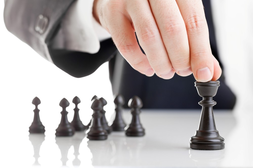 Business man moving chess figure with team behind - strategy or leadership concept